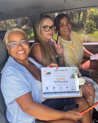 Three travelers smiling inside our van with their welcome sign
